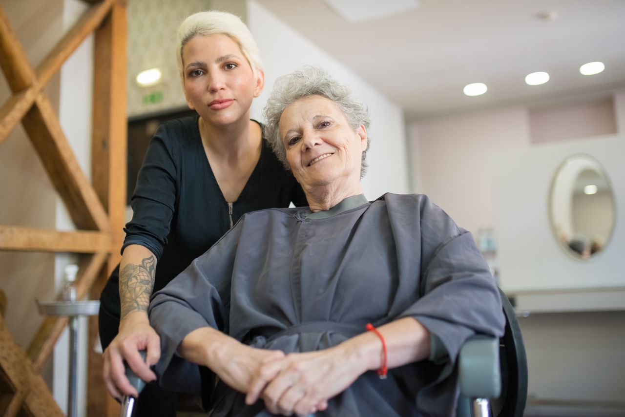 about-us Senior woman enjoying a hairdressing session at a salon in Portugal, with a friendly stylist.
